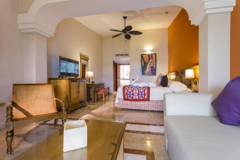 Suite con techo alto, cama y zona de estar del Grand Palladium Riviera Maya