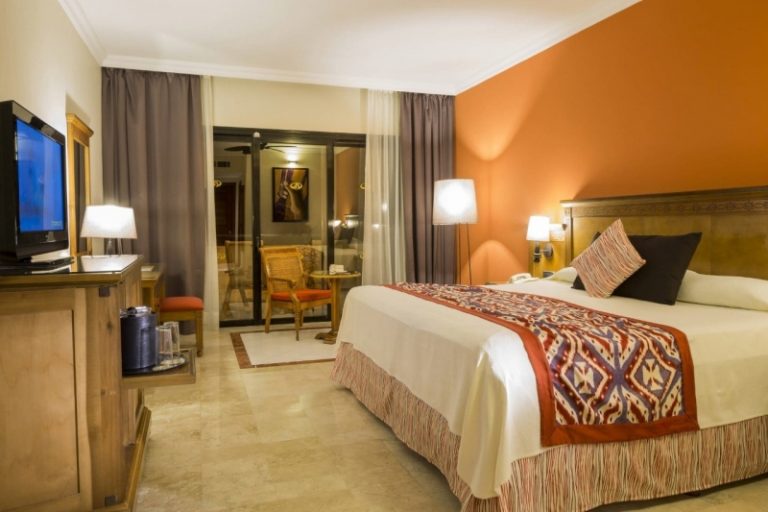 Habitación con cama de matrimonio y pared naranja del Grand Palladium Riviera Maya