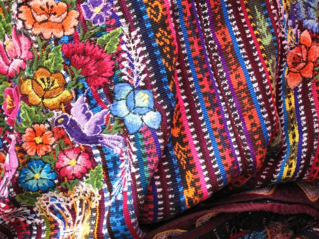 Bordado mexicano de flores de colores junto a un tejido de telar a rayas