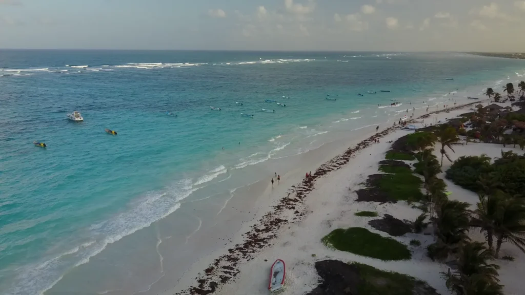 Playa larga de la Riviera Maya vista desde el aire, con barcas fondeadas